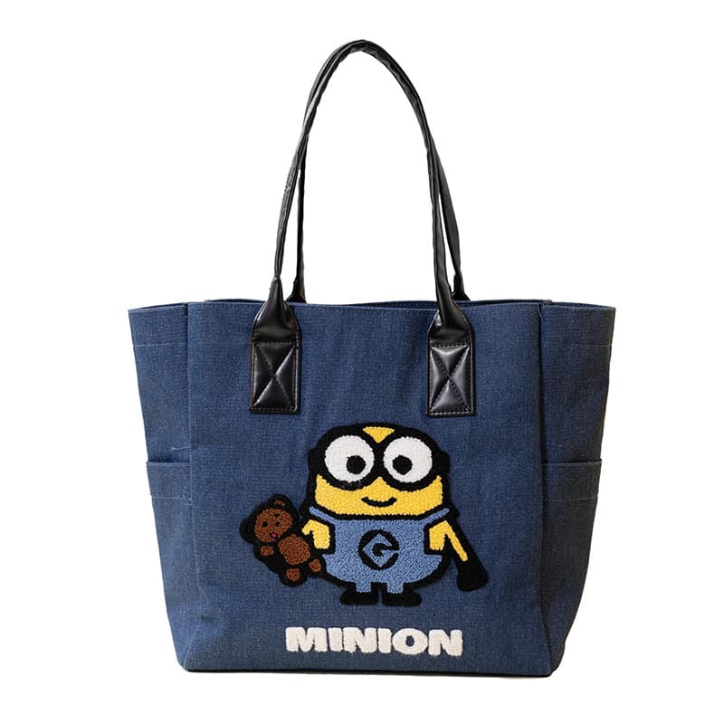 Blue denim tote bag featuring an embroidered Minion holding a teddy bear above white text.
