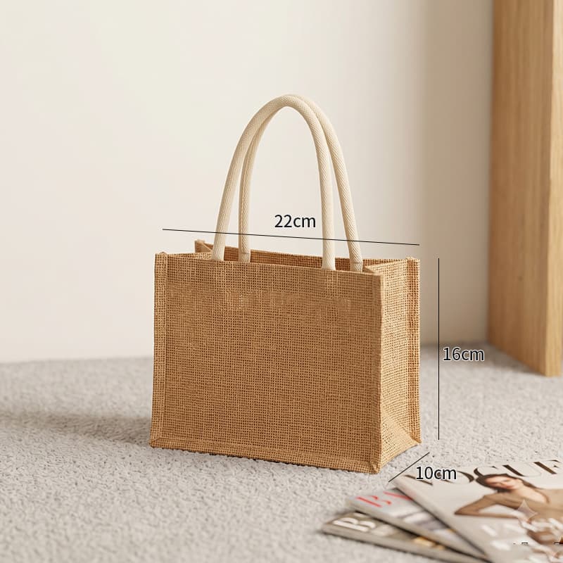 Small jute tote bag with cream handles, measuring 22cm by 16cm by 10cm.